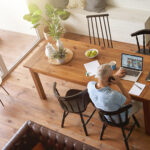 Top view of a mature caucasian businessman sitting at table in his modern apartment and working online on laptop